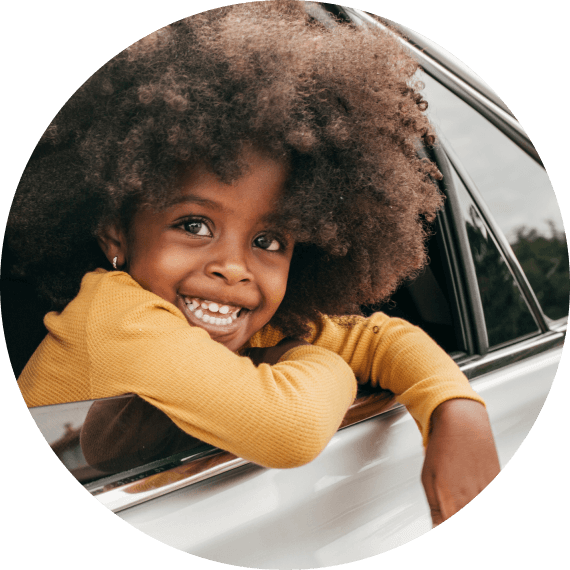 A young girl smiling through a car window